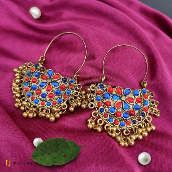 This is a pair of Red and blue stone studded earring. It is having small hanging golden coloured balls. It'll match with your red and blue dress.